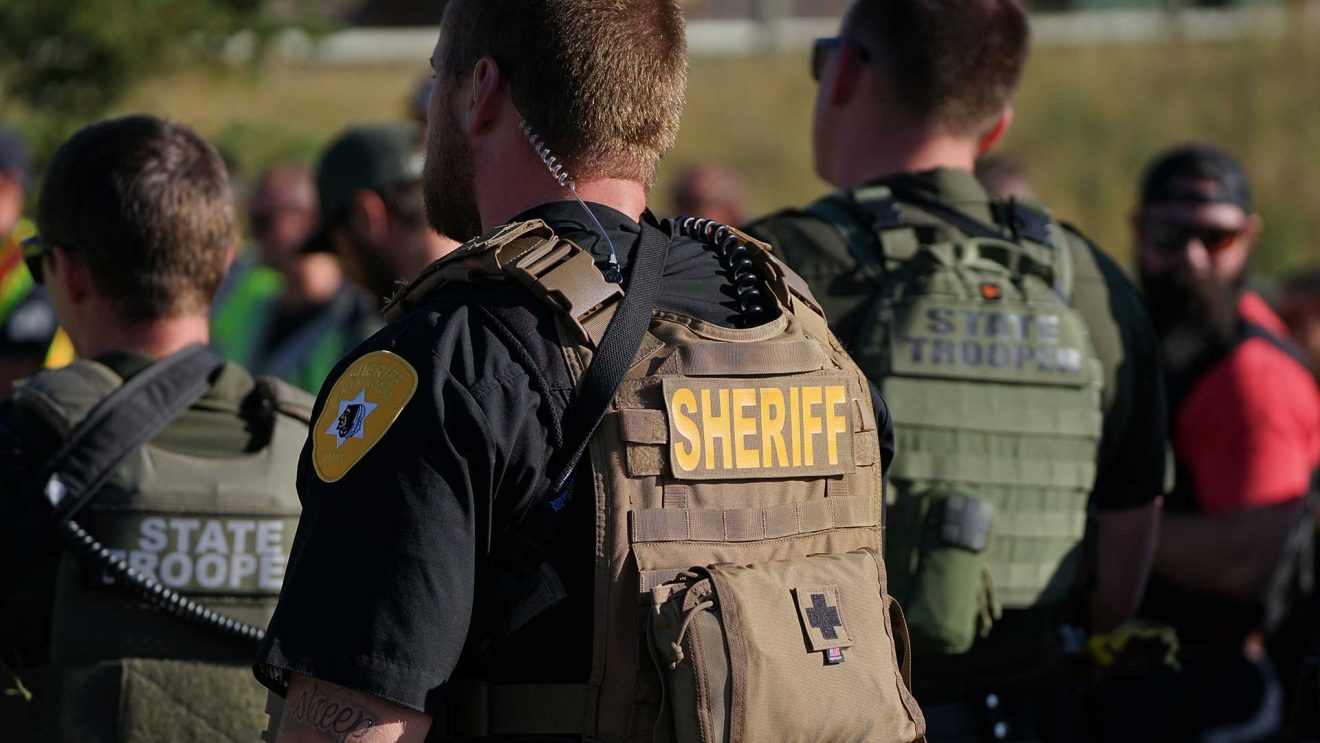 Backs of a row of law enforcement officers lined up.