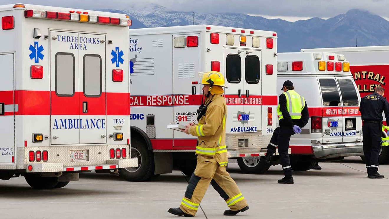 Firefighter in front or a row of ambulances.